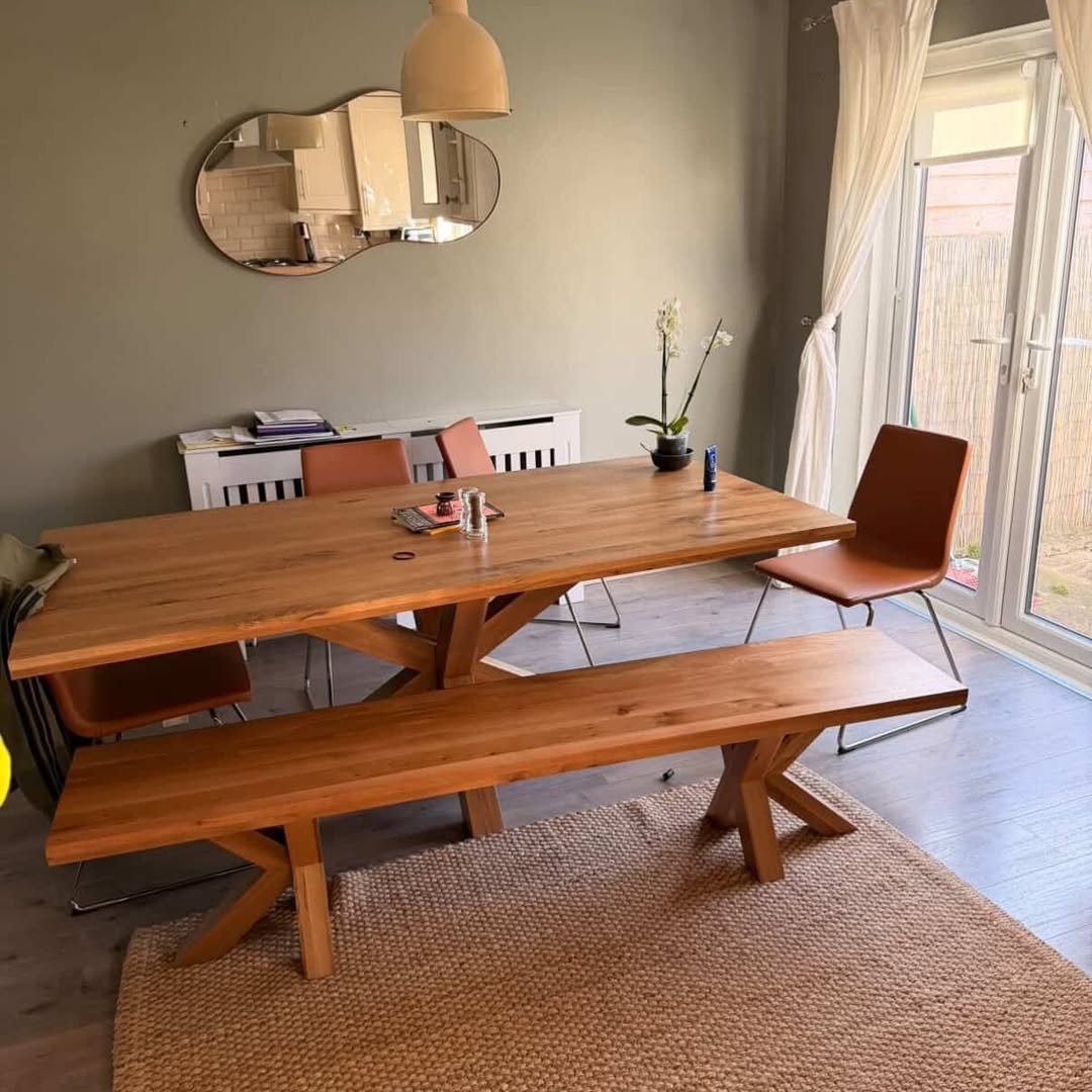 Dining room with wooden table, bench, chairs, and jute rug.