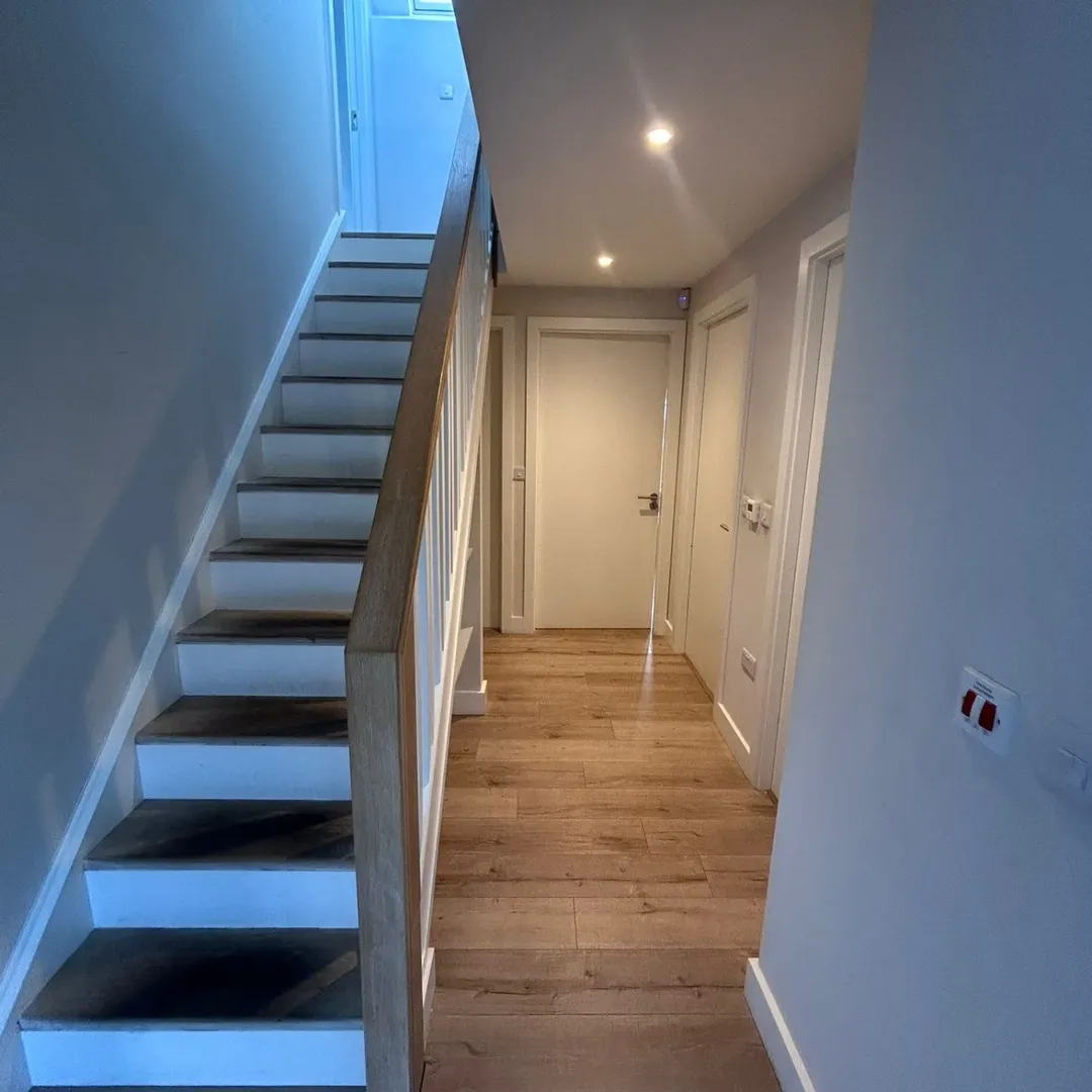 Hallway Stairs Wood Floor White Doors Hallway with stairs, wood floor, and white doors.