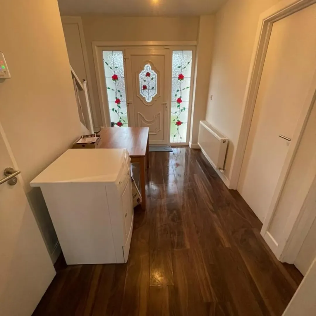 Hallway with wood floors, white walls, door with rose stained glass.