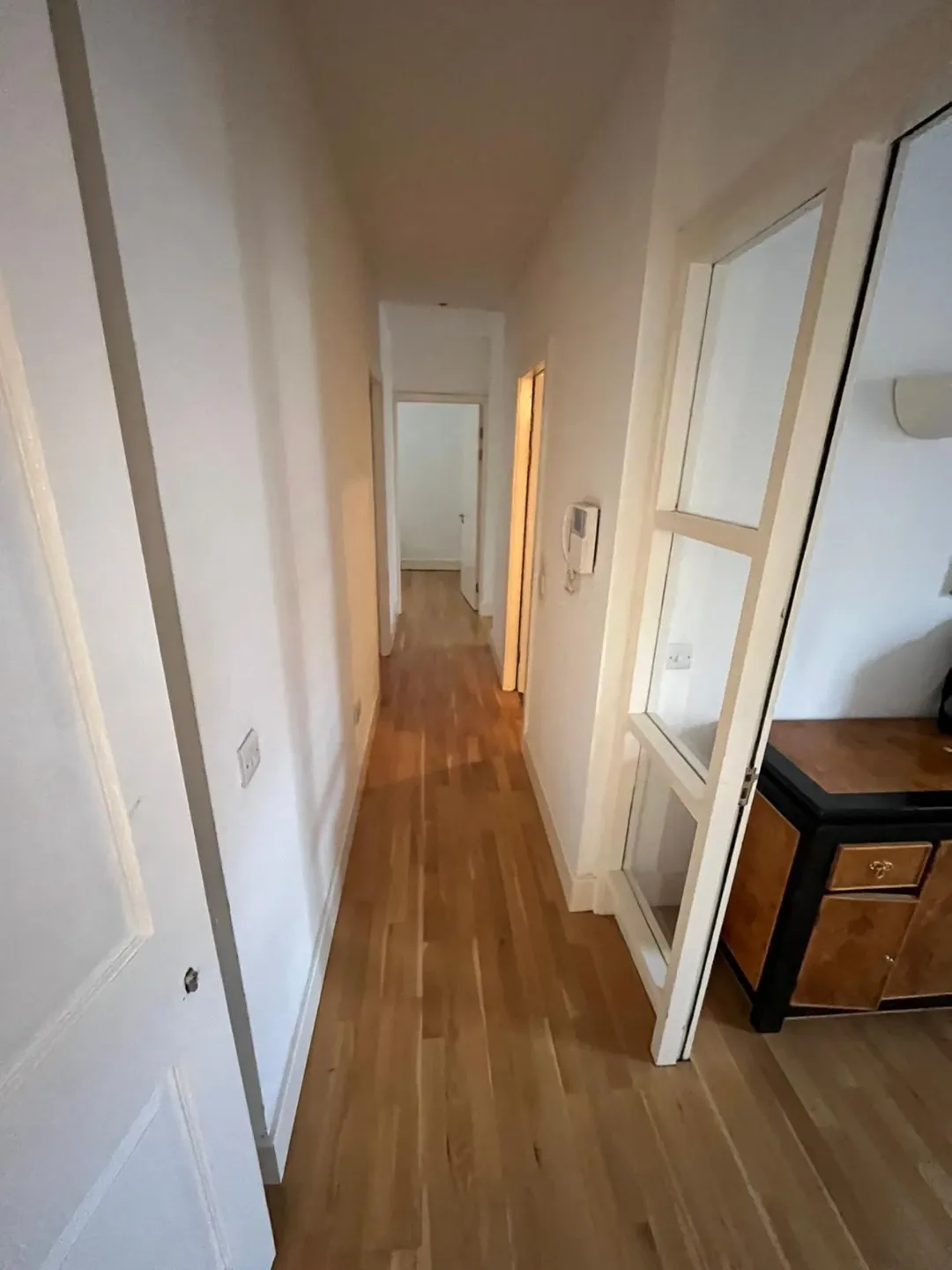Hallway Wood Floor White Walls Hallway with wood flooring, white walls, and doorway view.