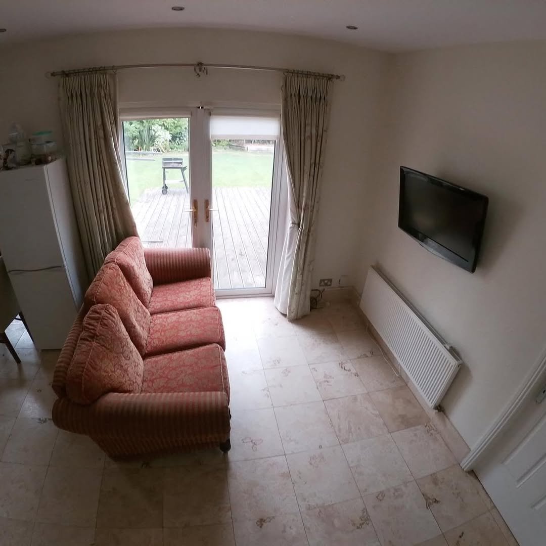 Living Room Red Sofa Patio Doors Living room with red sofa, TV, radiator, and patio doors leading to garden.