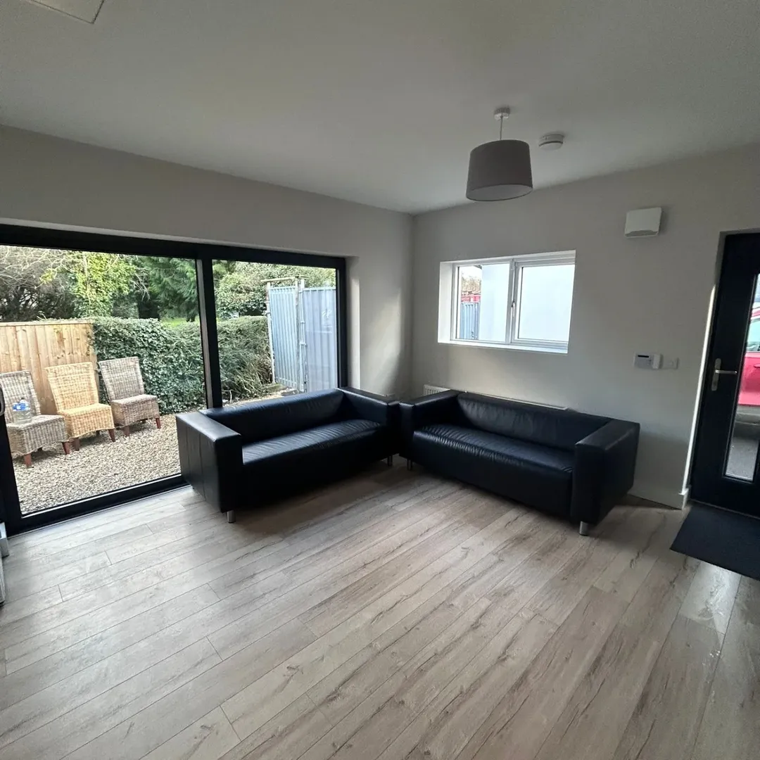 Modern Living Room Black Sofas Wood Floor Modern living room with black sofas, wood floors, sliding glass doors, and outdoor seating area.