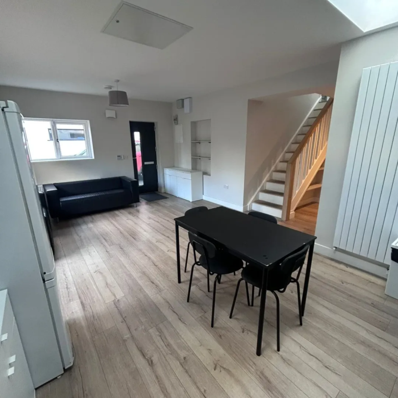Living room with black dining set, couch, and staircase.