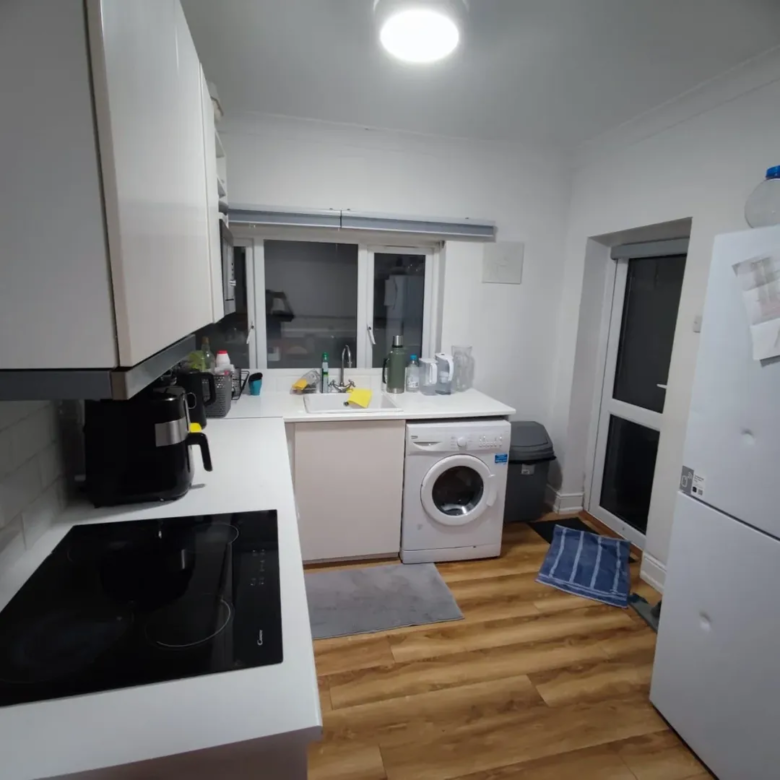 Modern kitchen featuring white cabinets, appliances, and wood-style flooring.