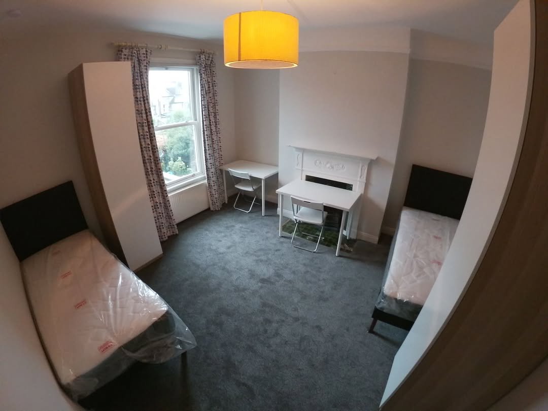Shared Bedroom Two Beds Desks Wardrobes Shared bedroom with two beds, desks, wardrobes, gray carpet, and a yellow lampshade.