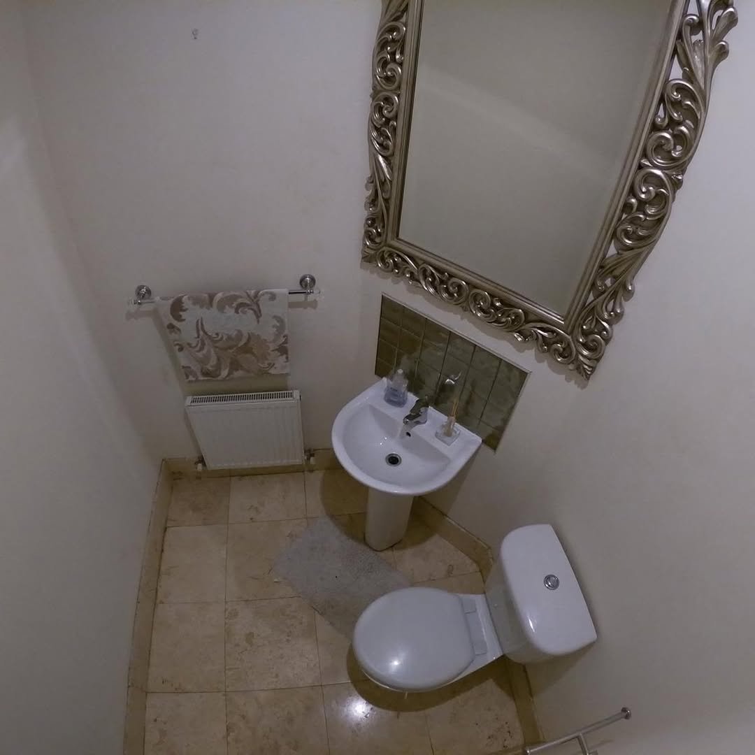 Small Bathroom Toilet Sink Mirror Small bathroom with toilet, sink, ornate mirror, and beige tile floor.