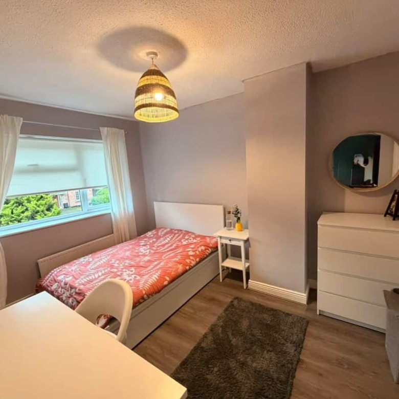 Cozy bedroom with single bed, desk, and modern decor. Natural light from window.