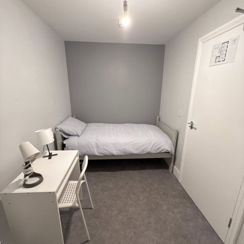 Small bedroom with single bed, desk, and minimal decor in a compact space.