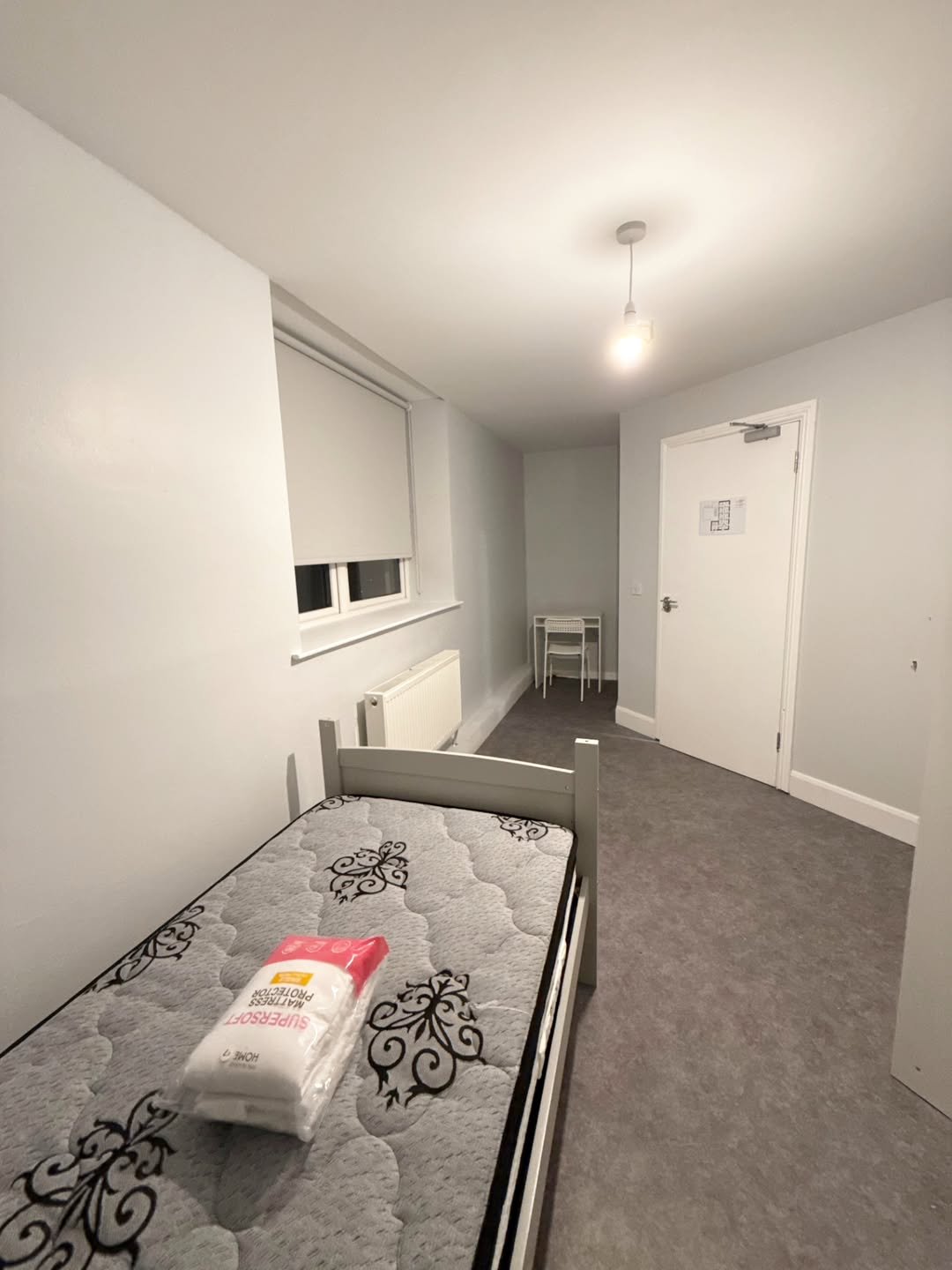 Small, modern dorm room with a single bed and desk area.