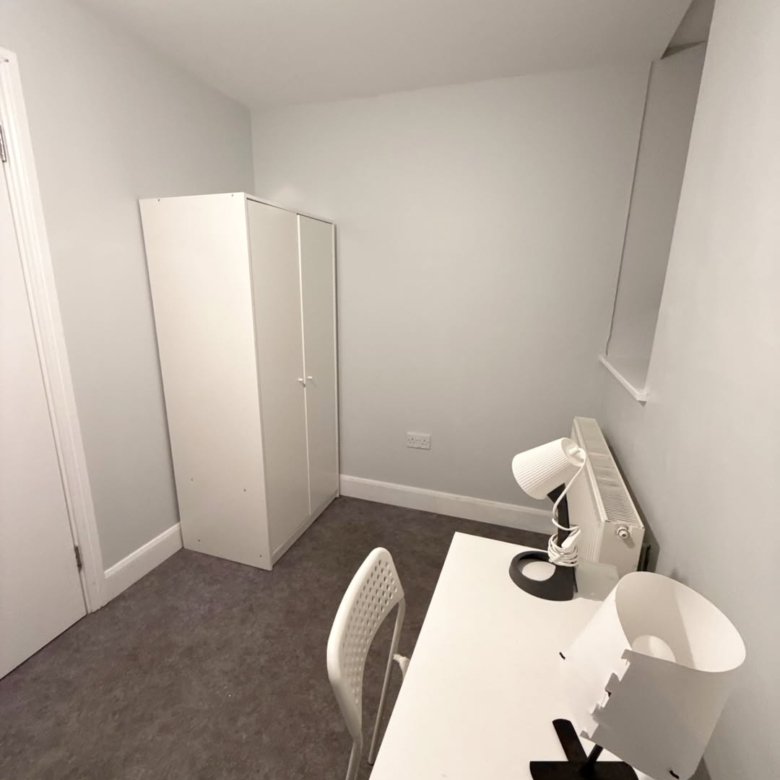 Small room with white wardrobe, desk, chair, and two lamps.