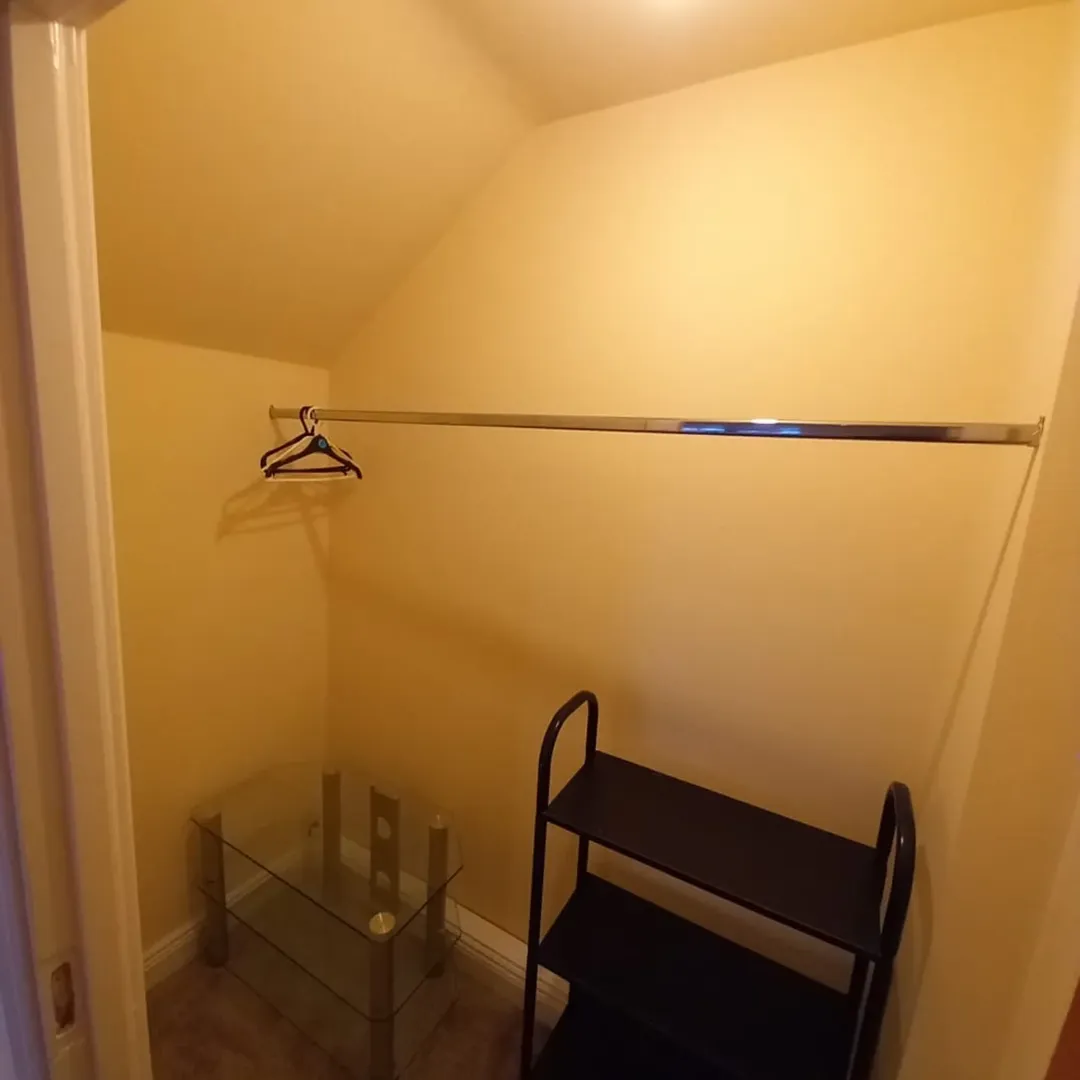 Small Walk In Closet Shelving Table Small walk-in closet with metal rod, glass table, and black shelving unit.