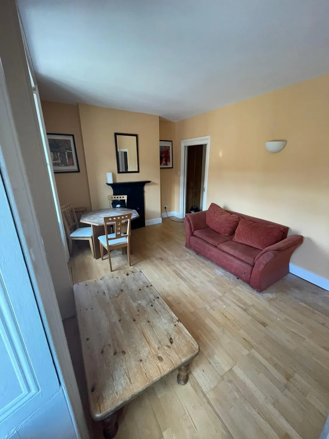 Living room with red sofa, dining table, and wooden coffee table in a cozy, vintage-style interior.