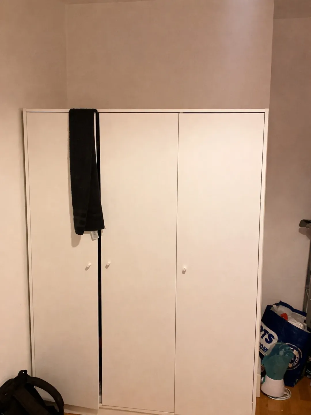 White Wardrobe Black Scarf Shopping Bag White wardrobe with black scarf hanging on door and shopping bag on floor.