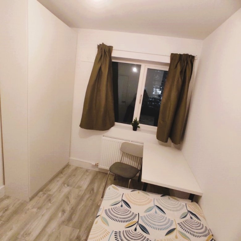 Cozy bedroom with bed, desk, chair, and wardrobe, featuring a window with brown curtains. – Ghar.ie property listing