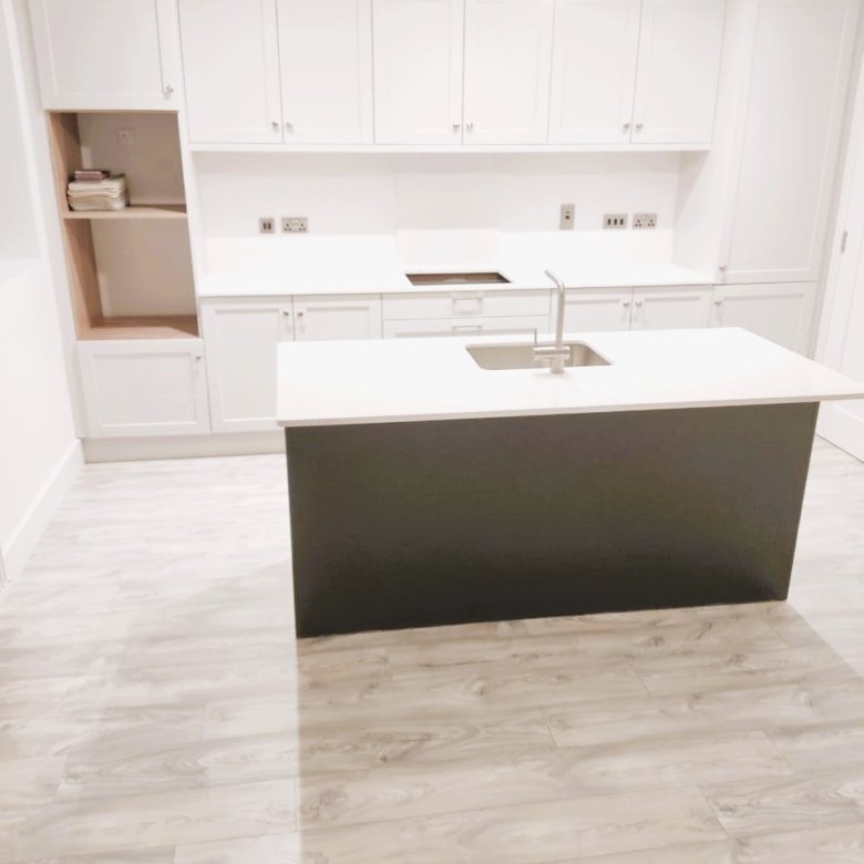 Modern kitchen island with dark base and white countertop, featuring a sink and faucet. – Ghar.ie property listing