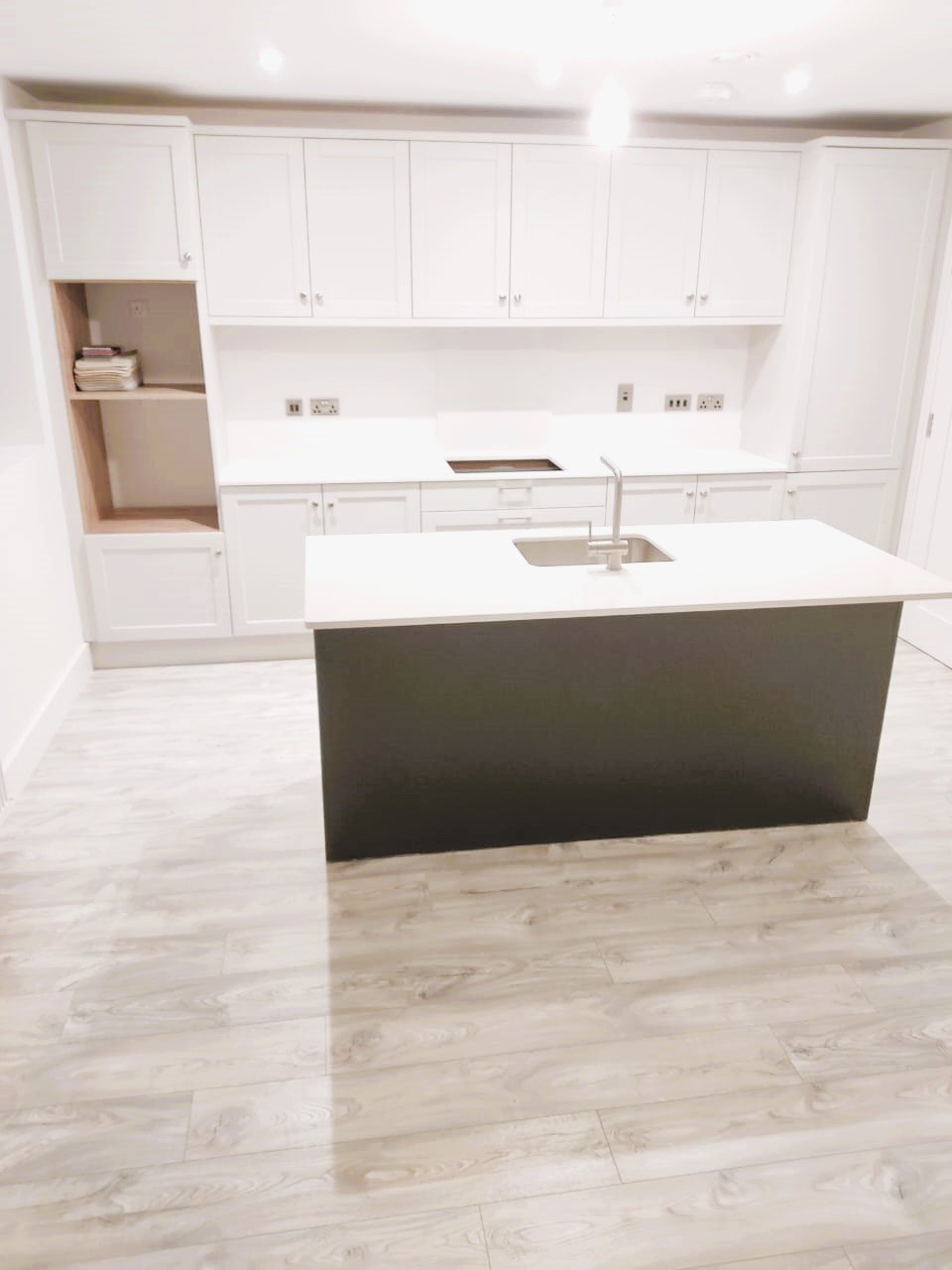 Modern kitchen island with dark base and white countertop, featuring a sink and faucet. – Ghar.ie property listing