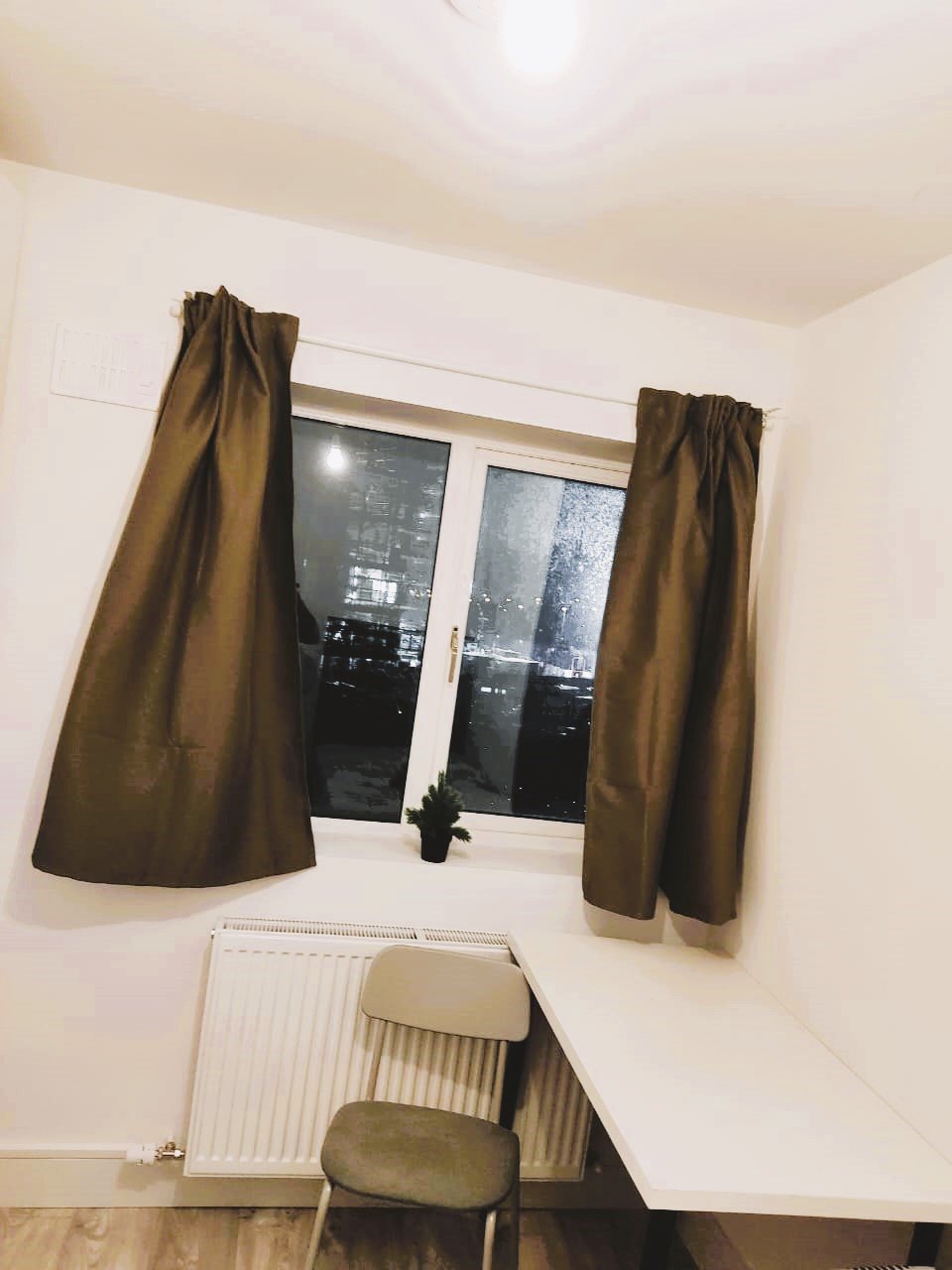 Cozy room with window view of city lights at night and a small desk. – Ghar.ie property listing