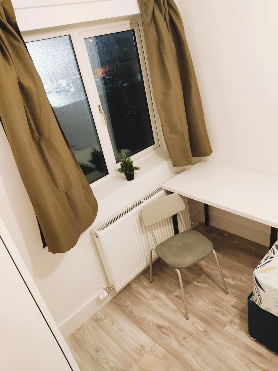 Small room with desk, chair, radiator, and window with brown curtains. – Ghar.ie property listing