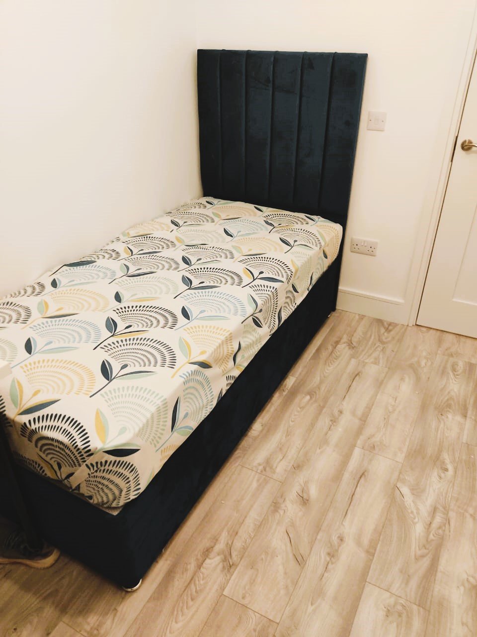 Single dark teal upholstered bed with a botanical print duvet in a bedroom. – Ghar.ie property listing